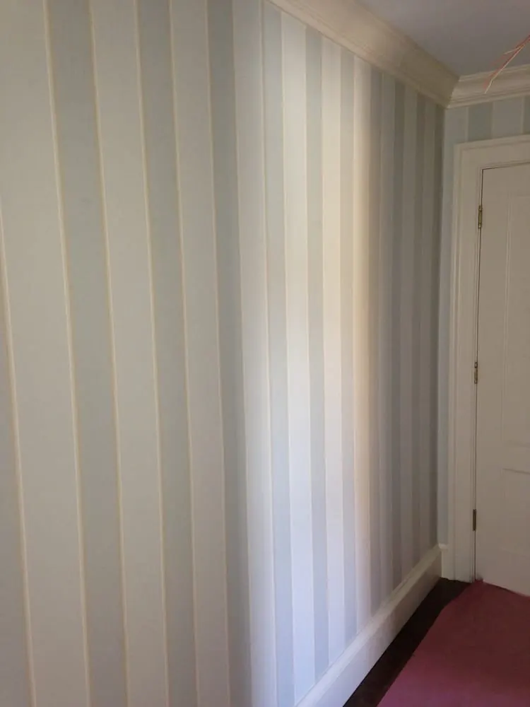 Blue and cream striped wallpaper with white crown molding and baseboard